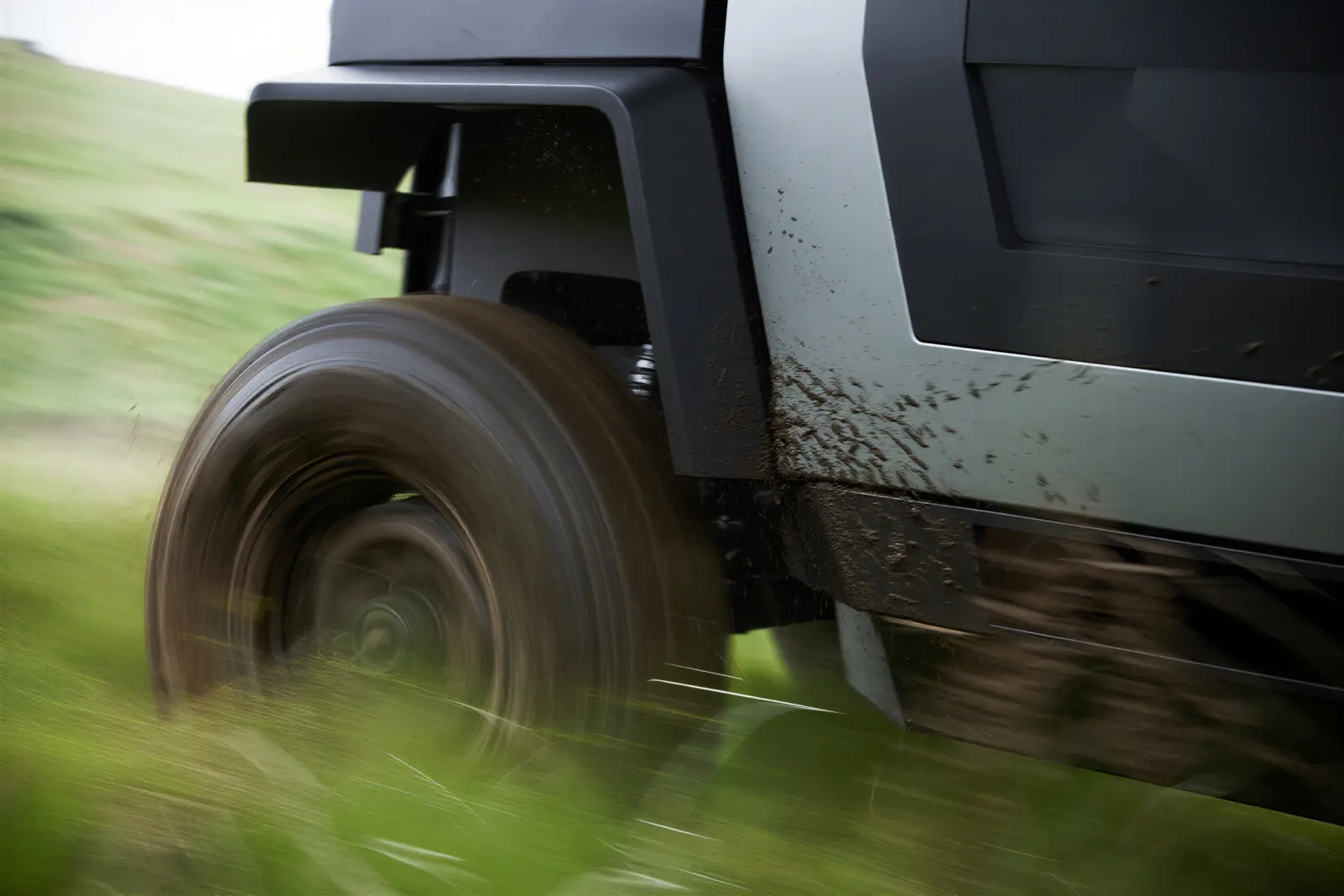 Front wheel in motion throwing mud on a grass slope